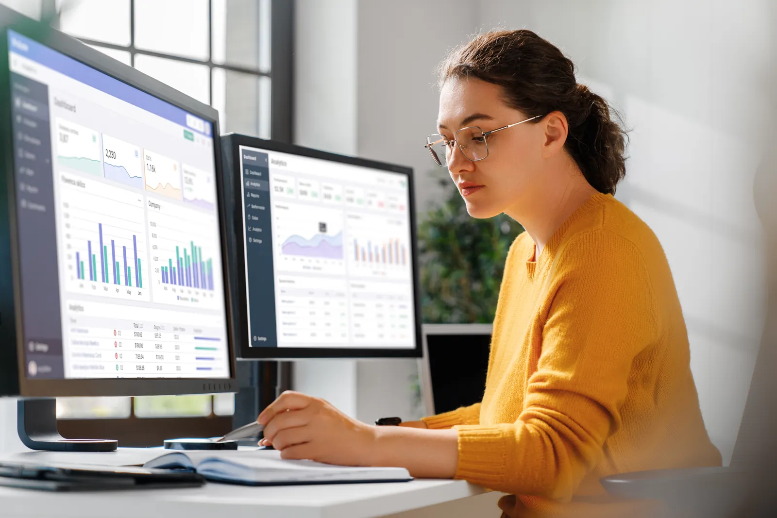 IT-Administratorin überwacht an zwei Monitoren Dashboards für Patchmanagement und Monitoring