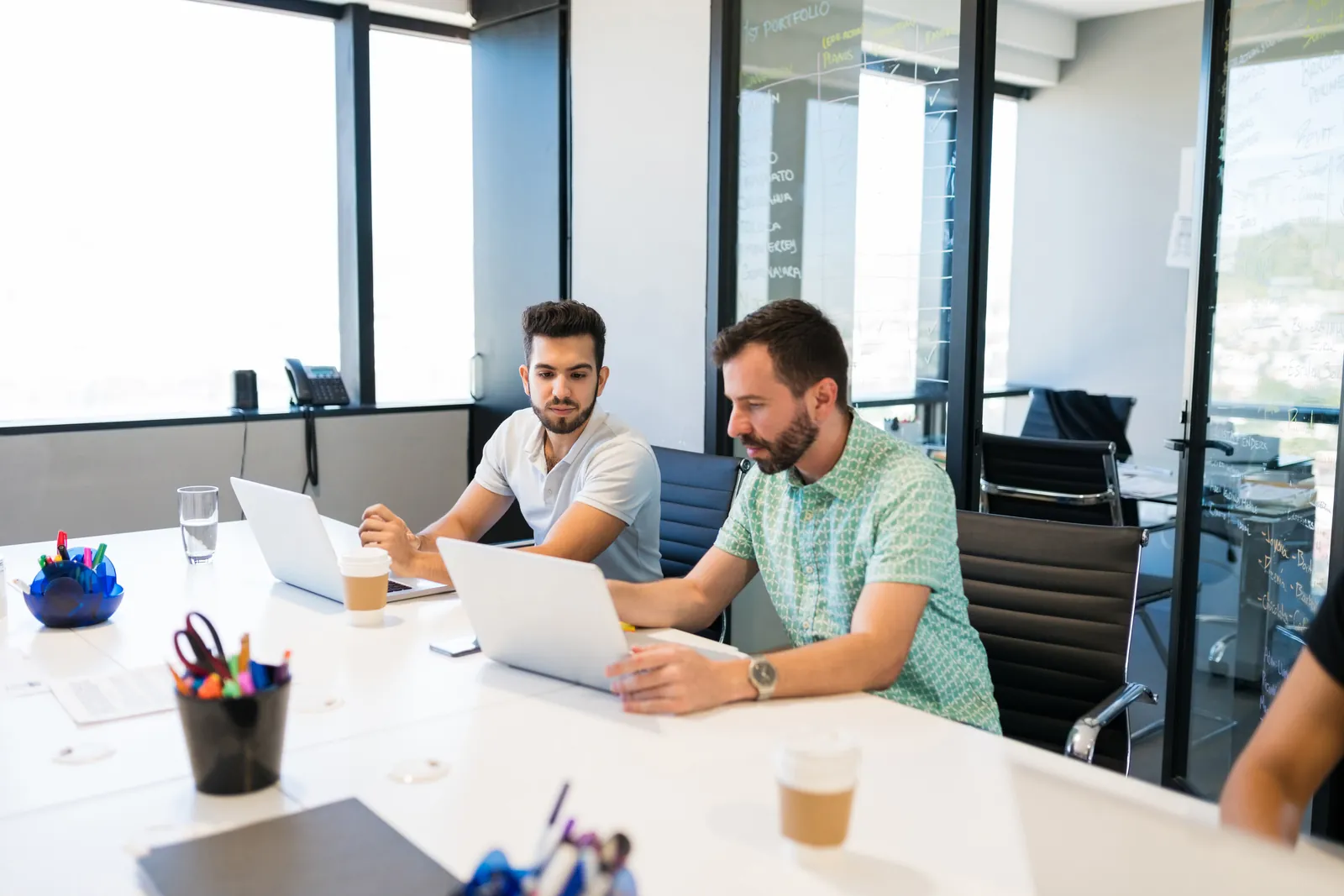 IT-Team plant am Besprechungstisch mit Laptops eine Microsoft-365-Tenant-Migration