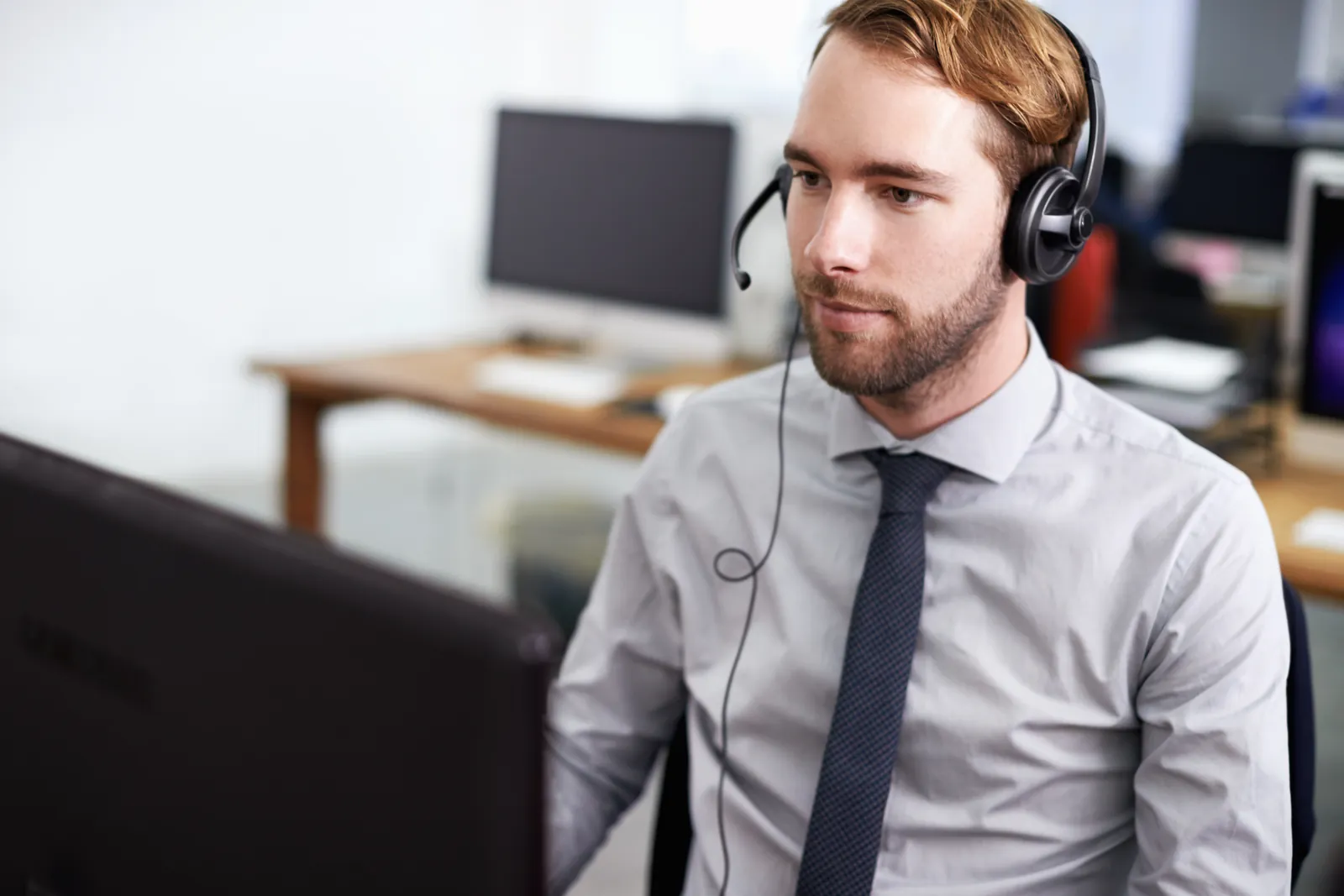 Support-Mitarbeiter mit Headset betreut Kunden im Rahmen von Managed Services