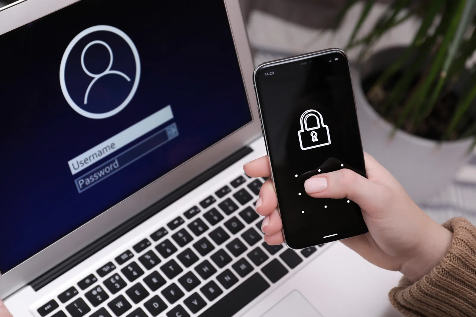 Laptop mit Anmeldemaske und Smartphone mit Schloss-Symbol für MFA zur Microsoft-365-Security