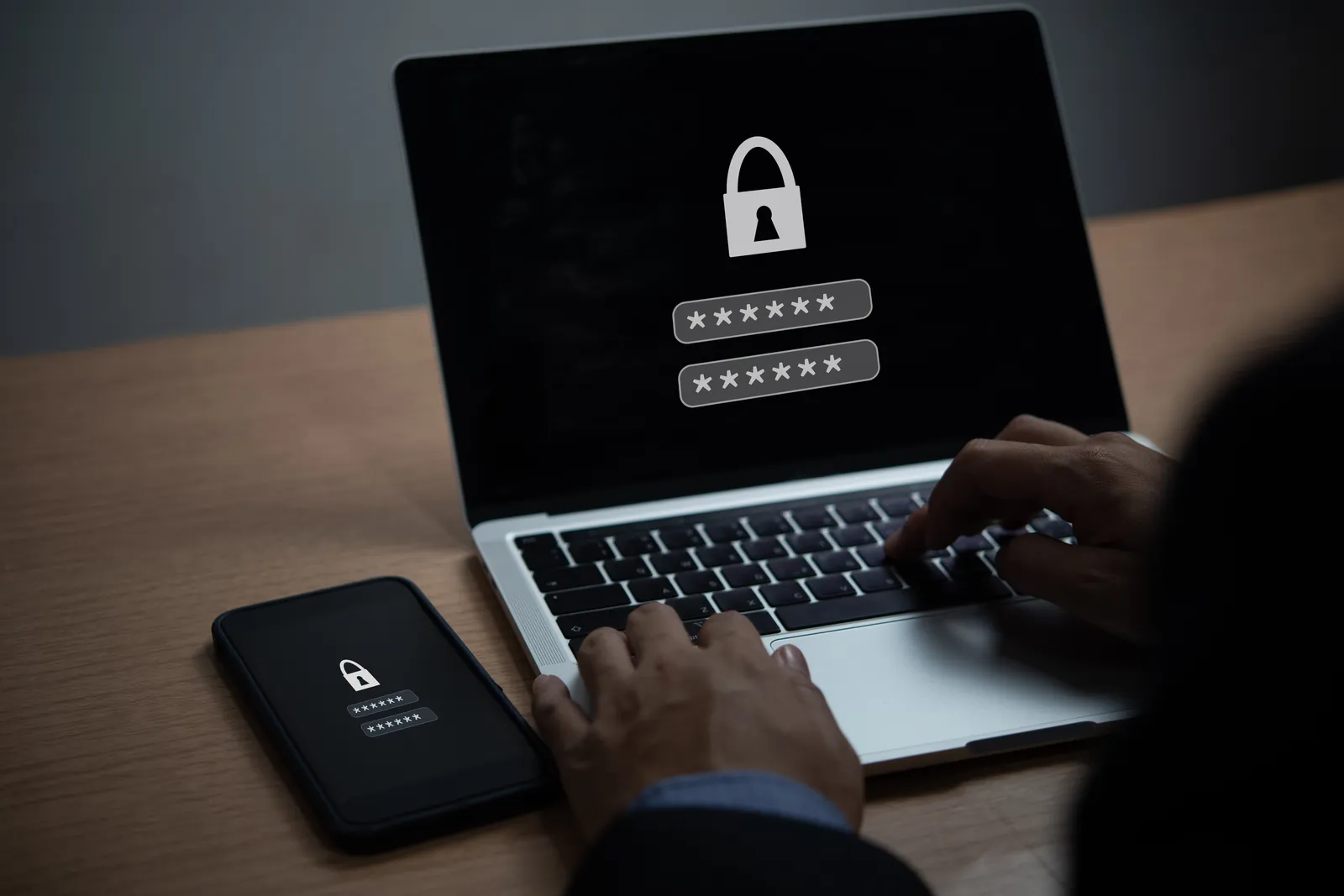 Laptop mit gesperrtem Passwortfeld und Smartphone daneben als Sinnbild für einen Passwortmanager für Unternehmen